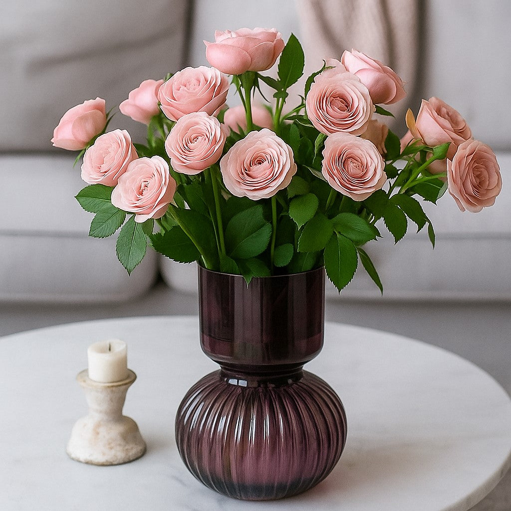 Vase rond en verre prune avec bouquet de roses, posé sur une table lumineuse pour une ambiance chaleureuse et moderne