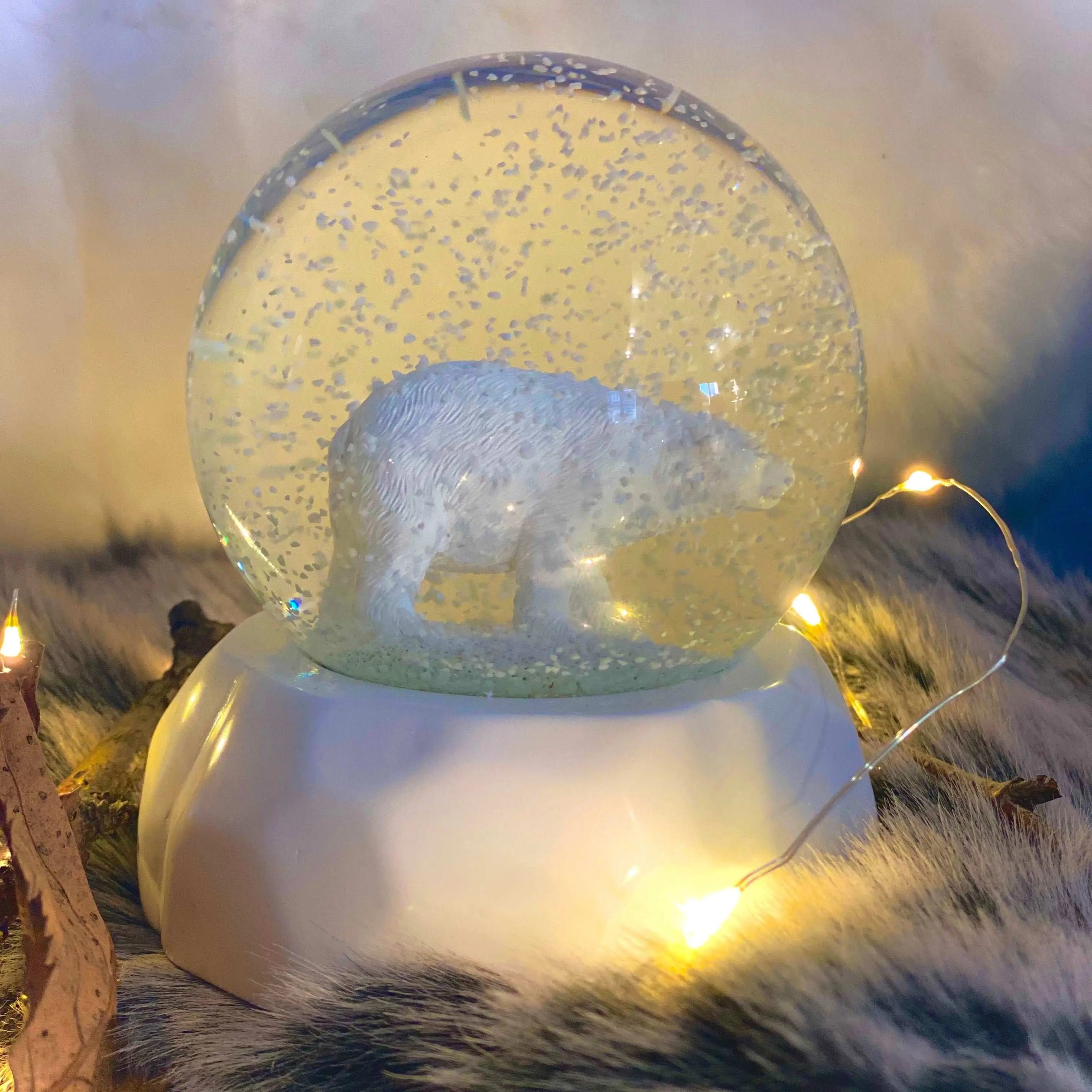 La boule à neige en verre, contenant une figurine détaillée d'un ours polaire sur un socle en résine, est une décoration unique pour votre maison ou bureau